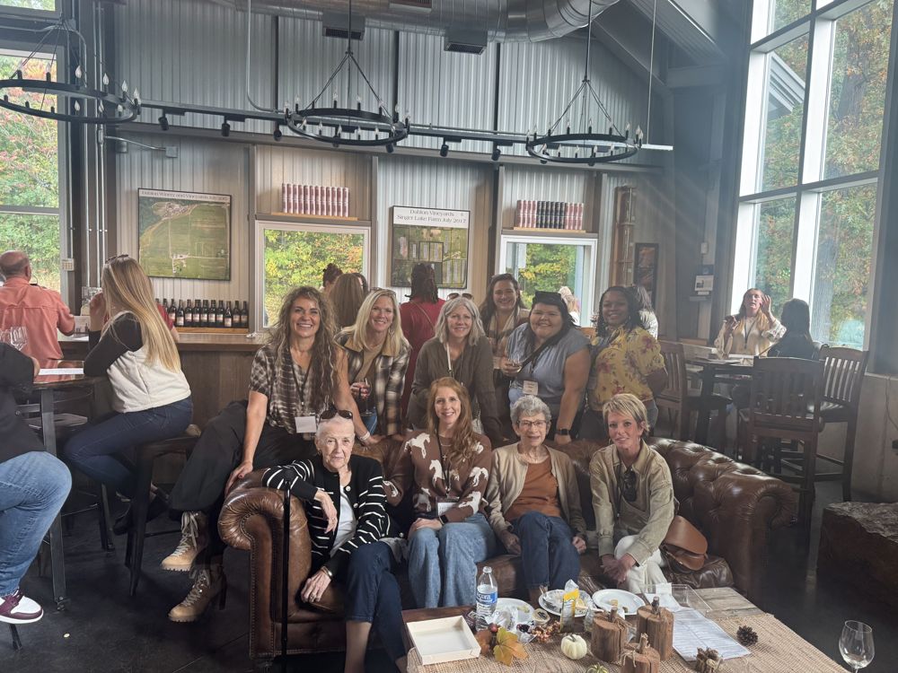 A women's networking group gathered on leather couches in a taproom